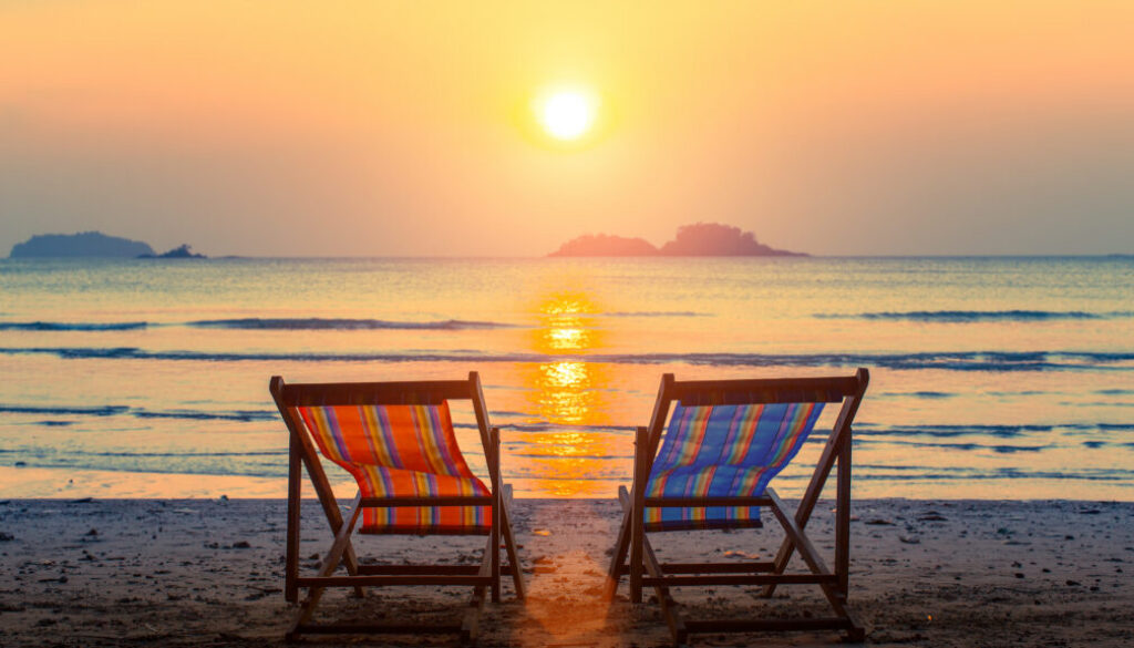 Pair of beach loungers on the deserted beach at sunset.